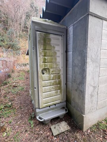 屋外に設置された仮設トイレの改修前